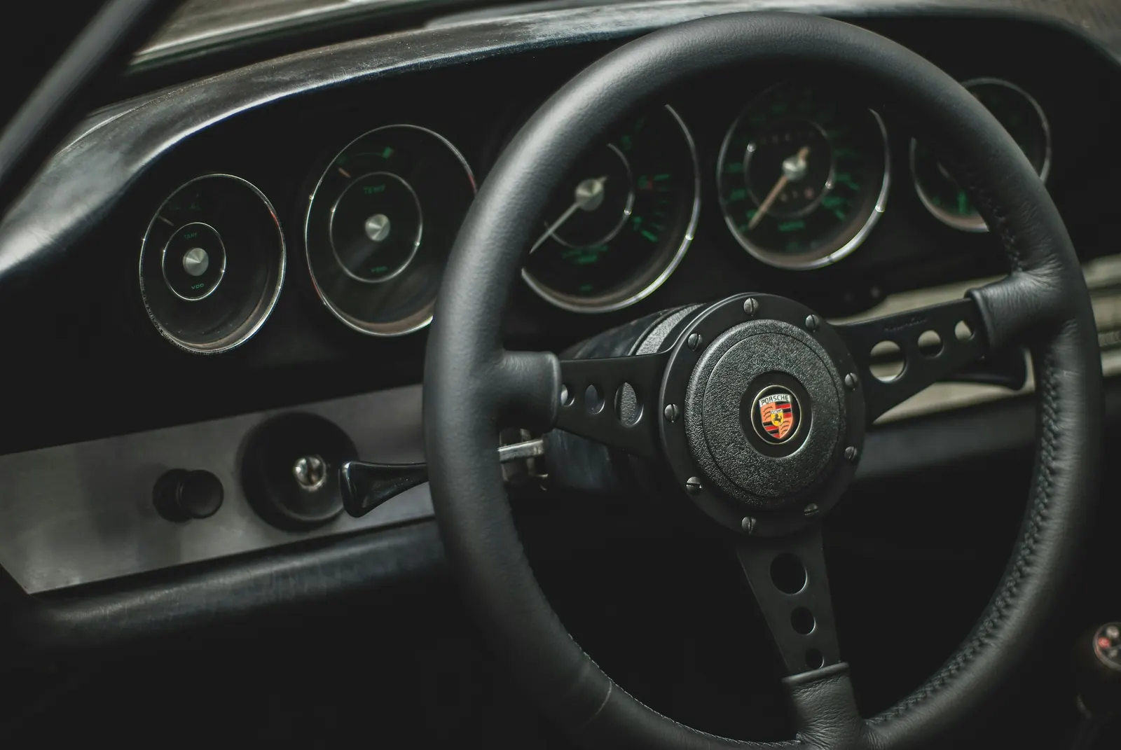 Painel e volante de um Porsche clássico na penumbra